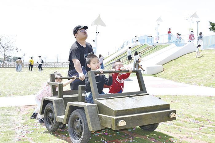 木製軍事車輛廣受大小朋友歡迎，推著在公園裡跑。